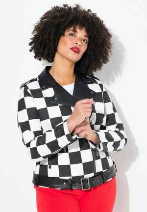 Black and white checkered jacket with a lapel collar, zippered front, and black belt. Worn over a white top and paired with red pants.
