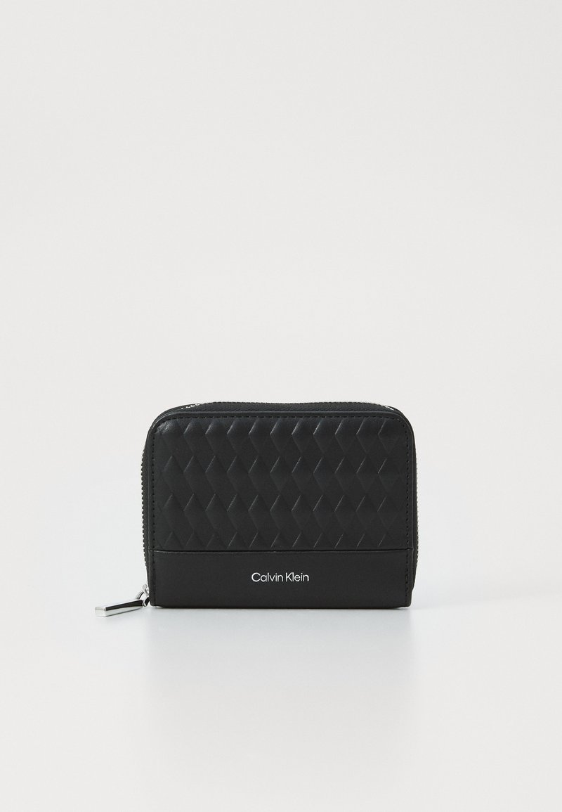 Black zippered wallet with a quilted texture on the front, smooth sides, and embossed "Calvin Klein" logo. Compact and rectangular shape.