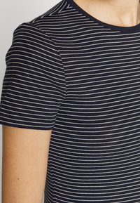 Tmavě modré pruhované tričko z měkké bavlny s krátkými rukávy, kulatým výstřihem a tenkými bílými vodorovnými pruhy po celém povrchu.