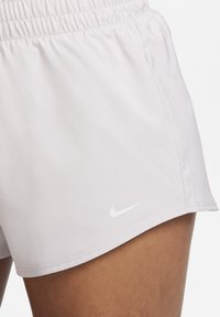 Pantalones cortos deportivos de color rosa claro con una cinturilla elástica. Presentan un pequeño logo blanco de Nike en el lado inferior y están hechos de una tela suave y ligera.