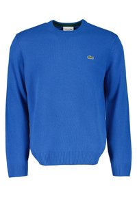 Blå stickad tröja av mjukt material med rund halsringning, ribbade ärmslut och nederkant, samt en grön Lacoste-logotyp på vänster bröst.