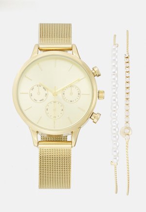 Montre-bracelet en or avec un bracelet en maille et trois petits cadrans à côté de deux bracelets en or, l'un avec des perles blanches et l'autre avec des pierres transparentes.