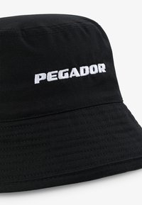 Fekete vödörsapka tartós anyagból, az elején varrott fehér "PEGADOR" logóval. Kofferréteges felület, széles, lefelé hajló peremmel.