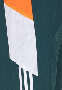 Tissu bleu sarcelle avec panneau triangulaire orange et blanc attaché, et trois rayures blanches verticales.