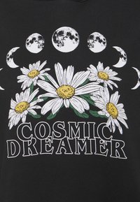 Černá látka s bílým grafickým designem sedmikrásek se žlutými středy a fázemi měsíce, doplněná textem "KOSMICKÝ SNÍLEK."