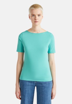 Turquoise top met korte mouwen in een gladde stof, voorzien van een wijde halslijn en een getailleerde pasvorm, gecombineerd met lichtblauwe jeans.
