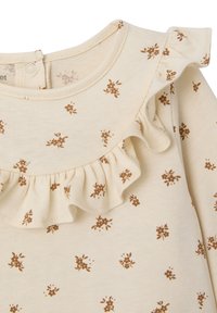 Cream-colored top with small brown floral print and a ruffle around the neckline. Made of soft fabric with a smooth texture.