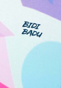 BIDI BADU-gemarkeerde stof met abstracte vormen in paars, roze en lichtblauw, met een gestructureerd oppervlak en vet, donker letters.