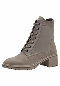 Bottines beiges en daim lisse, avec un laçage à l'avant, bout rond et un talon bloc texturé avec une semelle à motifs.