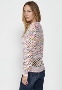 Pull en tricot avec un motif multicolore pastel, présentant un tissage lâche et des poignet en côte. La coupe est décontractée avec un col rond.