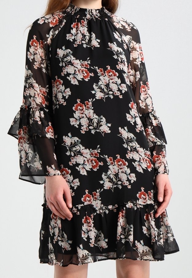Robe noire à fleurs roses et rouges, manches longues transparentes avec poignets volantés et ourlet volanté fluide.