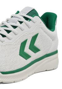 Białe buty sportowe z zielonymi akcentami, siateczkowa cholewka, gładka podeszwa i teksturowane logo w kolorze zielonym. Wyposażone w białe sznurowadła i wyściełany kołnierz.