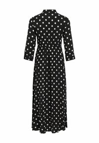 Černé šaty s bílými puntíky, s košilovým límcem, dlouhými rukávy a elastickým páskem, které sahají až k kotníkům.