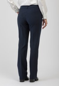 Pantaloni a righe navy realizzati in tessuto, con un taglio slim fit e gamba dritta. Tasche visibili e passanti per cintura, texture opaca.