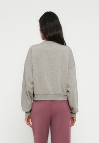 Γκρι, υπερμεγέθη φούτερ με στρογγυλή λαιμόκοψη και υποβαθμισμένους ώμους. Απαλή υφή, κομμένο μήκος και ελαστική μέση. Συνοδεύεται από ροζ παντελόνια.