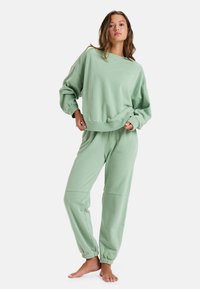 Mint green cotton loungewear set features a relaxed-fit sweatshirt with dropped shoulders and elastic cuffed joggers for comfort.