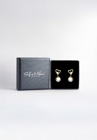 Guldörhängen formade som hjärtan med vita pärlor, visade i en svart texturerad smyckeskrin med sammetsfoder.