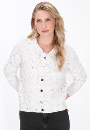 Witte gebreide cardigan met zwarte spikkels, ronde kraag en sluiting met knopen aan de voorkant. Beschikt over geribbelde manchetten en zoom. Zachte textuur.