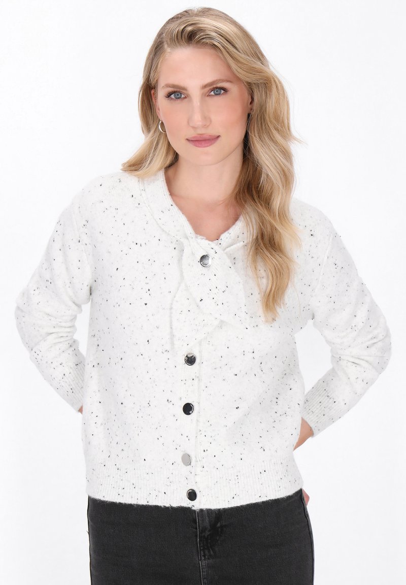 White knitted cardigan with black speckles, rounded collar, and front button closure. Features ribbed cuffs and hem. Soft texture.