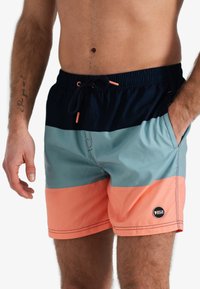 Zwemshorts voor heren met een kleurvlakontwerp in marineblauw, teal en koraal. Gemaakt van lichtgewicht materiaal met een elastische tailleband en een trekkoord.