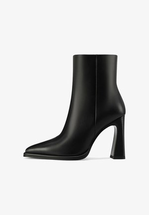 Stivaletto alla caviglia in pelle nera con punta appuntita e tacco alto a blocco, texture liscia, cucitura laterale visibile, su sfondo bianco.