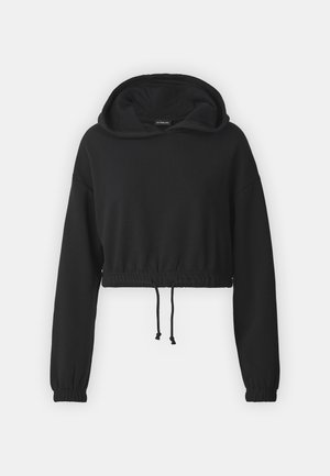 Črna skrajšana kapuca iz mehkega materiala, ki ima kapuco z vrvico, elastične manšete in zategnjen pas. Preprost, moderen dizajn.