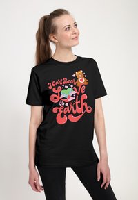 Sort bomulds t-shirt med et farverigt grafisk design med en Care Bear, Jorden og teksten "Jeg Care Bear Elsker Jorden" i rød og pink.