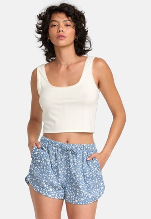 White cropped tank top with textured details and lace trim, paired with blue shorts featuring a white floral pattern and an elastic waistband.