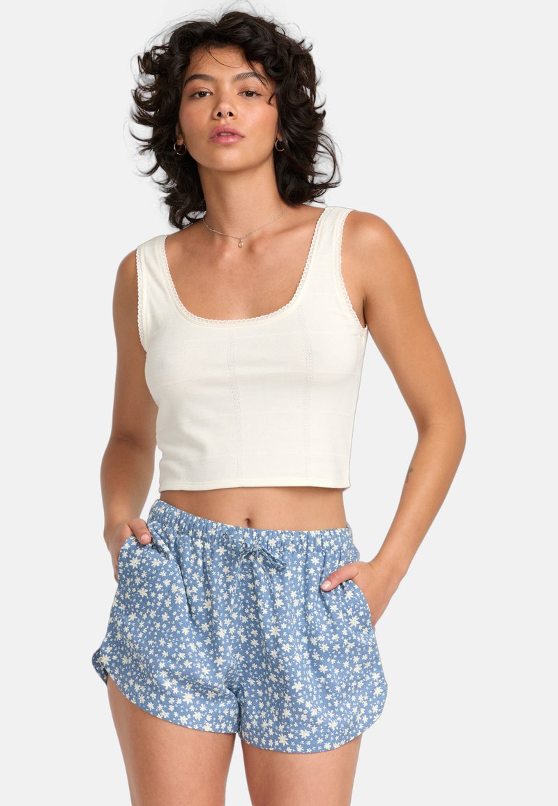 Hvid cropped tanktop med teksturerede detaljer og blondekant, parret med blå shorts med et hvidt blomstermønster og elastisk talje.