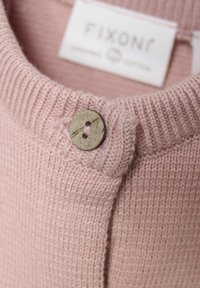 Hellrosa Strickpullover mit geripptem Kragen und einem Messingknopf-Akzent. Der Stoff ist weich mit einer strukturierten Oberfläche. Das Etikett trägt die Aufschrift "FIXONI."