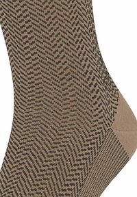 Braune gemusterte Socke aus weichem Material, mit einem Fischgrätmuster in Schwarz. Die Zehen- und Fersenbereiche haben eine glatte Textur.