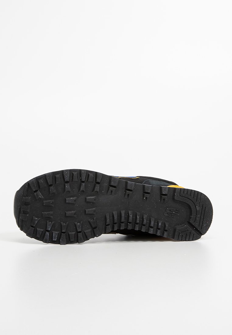 Zapato outdoor negro y amarillo con una suela de goma texturizada, que presenta un patrón de dibujo rugoso para una mejor tracción y estabilidad.