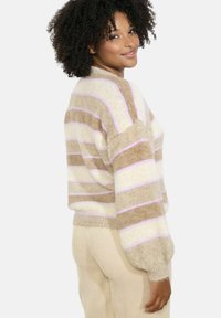 Svītrots džemperis bēšā un gaiši lavandas krāsā ar pūkainu tekstūru, lielizmēra piegriezums un riboti aproces. Apvienots ar krēmkrāsas ribotām biksēm.