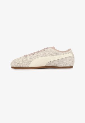 Beige sneaker met laag profiel en lichtbruine spikkels, witte streep aan de zijkant, lichtbruine veters en dunne bruine zool, vanuit zijaanzicht getoond.