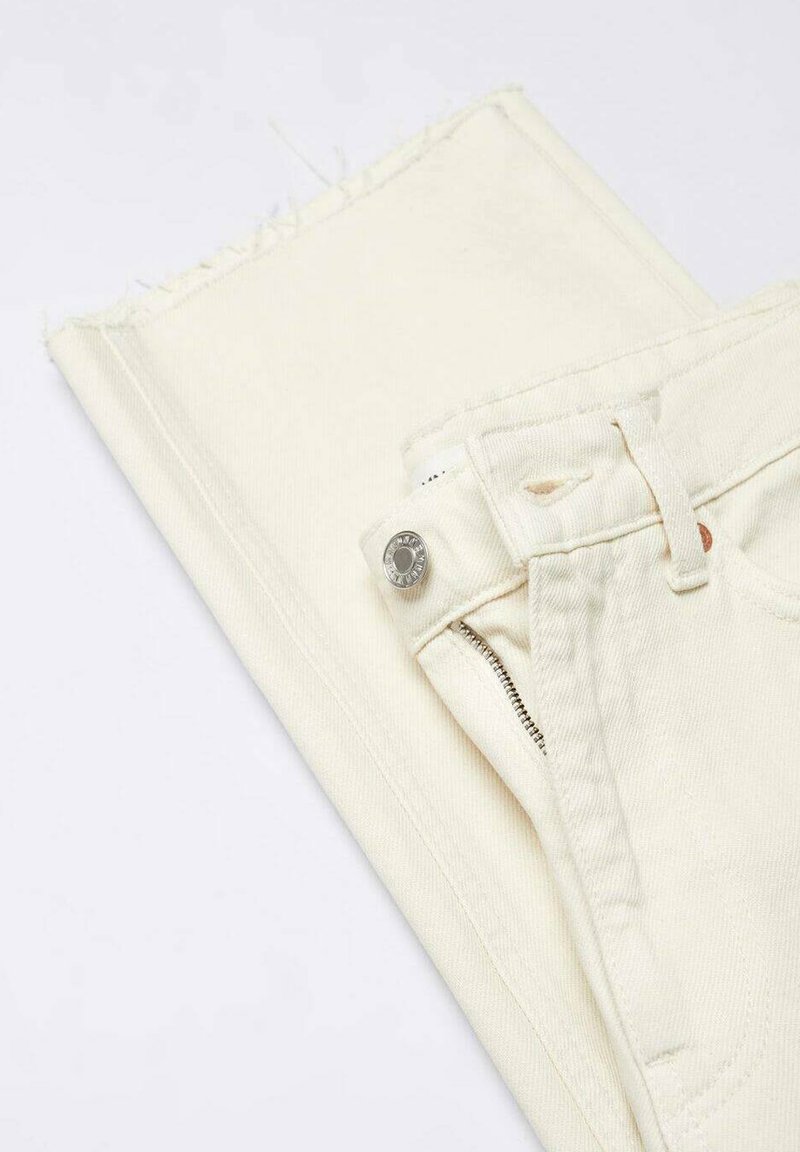 Weiße Jeans mit umgeschlagenem, ausgefranstem Saum. Mit einem silbernen Knopf und Reißverschluss, sowie dezenten Nähten in der Nähe des Bundes und der Taschen.