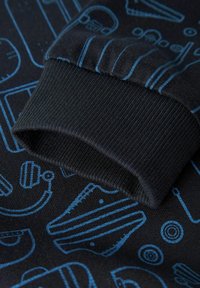 Svart gensererm med ribbet tekstur, med et blått grafisk design av forskjellige former og objekter over stoffet.