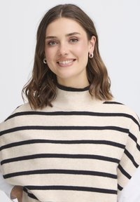Beiger gestreifter Pullover mit hohem Kragen, der marineblauen horizontalen Streifen und einem weichen, strukturierten Stoff aufweist. Lässiges Design mit Oversized-Schnitt.