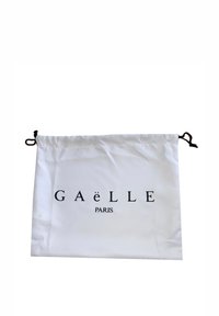 Sacchetto in tela con coulisse di colore bianco, con testo nero "GAëlle PARIS", caratterizzato da una superficie liscia e due coulisse nere per la chiusura.
