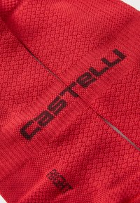 Chaussettes de cyclisme rouges avec un motif de tricot texturé, portant un logo "Castelli" en marron foncé. Le matériau est respirant et léger.