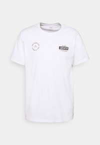 White cotton t-shirt with short sleeves. Features black printed graphics including "Levi's" logo and circular design on the front. Round neckline.