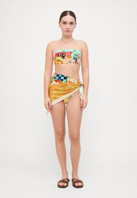 Bañador de dos piezas colorido que presenta un top bandeau con un estampado y un fondo envolvente en tonos naranjas. El material parece ligero y suave.