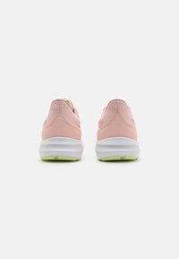 Chaussures de sport roses avec une surface texturée, semelle intermédiaire blanche et semelle extérieure verte. Dotées d'un talon rembourré et d'un design minimaliste.