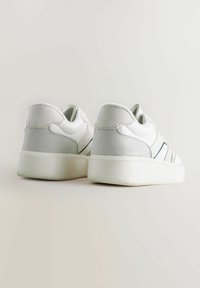 Sneakers bianchi con tomaia in pelle liscia, accenti in suede grigio e una suola in gomma spessa. Presentano un design minimalista e sottili strisce laterali.