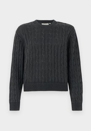 Mørkegrå kabelstrikket genser med lange ermer og ribbestrikkede mansjetter, kant og rund hals, vist på en ensfarget bakgrunn.