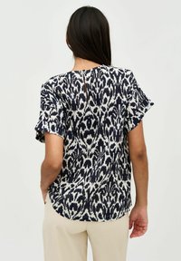 Blusa a maniche corte a righe navy e bianche, con orlo arrotondato e un piccolo taglio a forma di chiave sul retro. Tessuto di consistenza liscia.