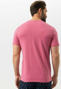 T-shirt met korte mouwen in effen roze stof, ronde hals, getailleerd ontwerp met een gladde textuur. Gecombineerd met donkergekleurde korte broek met patroon.