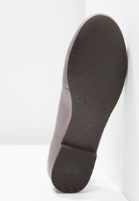 Semelle d'une chaussure en cuir marron montrant une semelle texturée, taille 37, avec marquage "Tamaris" et détail talon antidérapant.