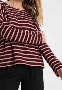 Langärmliges Oberteil mit horizontalen lila und rosa Streifen, runder Ausschnitt, lockere Passform und weichem Baumwollmaterial.