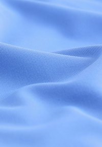 Lyseblåt, blødt stof med fin ribbet tekstur; blød fald med blide folder og subtil glans.