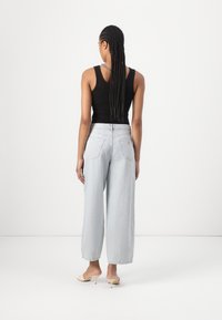 Lyseblå vid jeans med høy midje, med baklommer og oppbrettede hem, kombinert med en svart tank topp og nude hæl sanda.